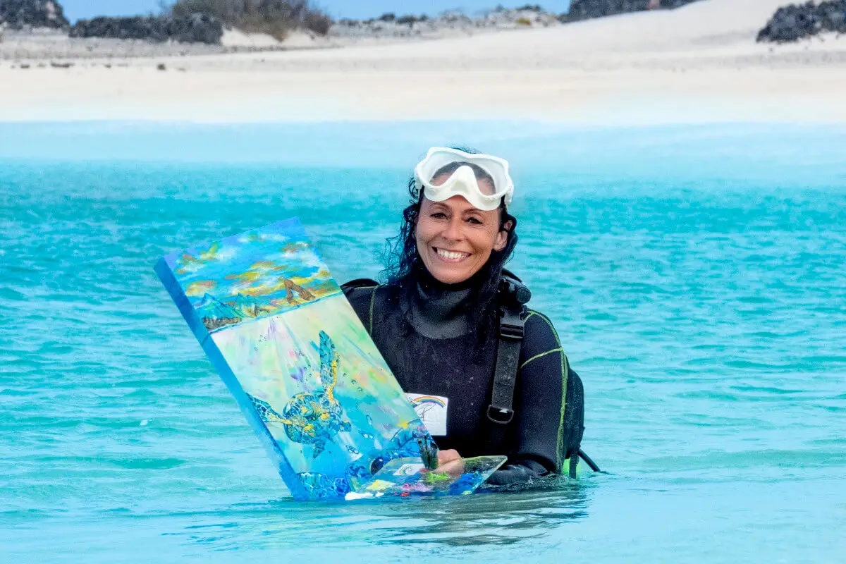 Ely Phenix retratada saliendo de las aguas de Fuenteventura y sujetando una de sus obras pintadas bajo el mar
